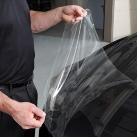 Personne appliquant un film de protection de peinture