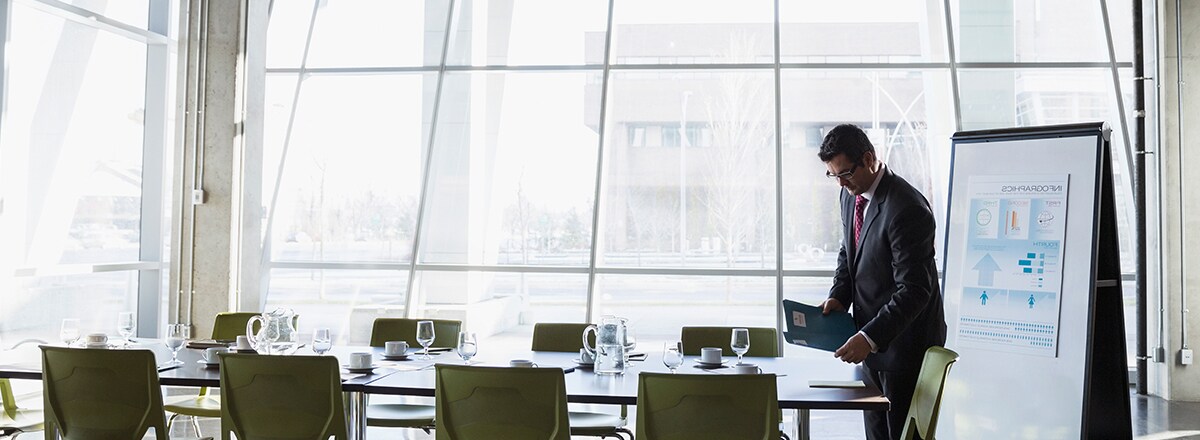 Homme se préparant pour une réunion dans une pièce avec de grandes fenêtres, protégées par des films 3M pour vitrages
